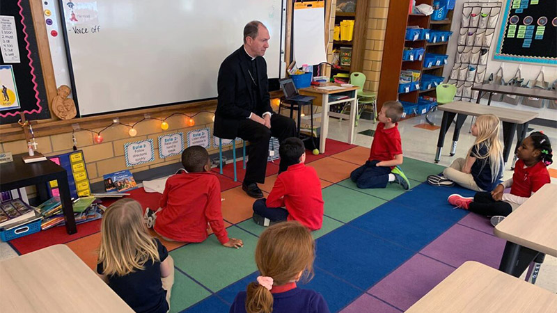 Image of bishop with school children in a classroom